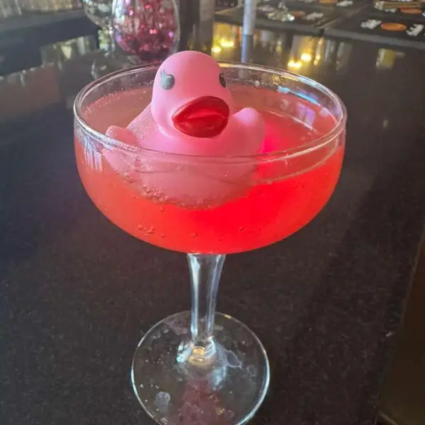 A pink cocktail served with a rubber duck